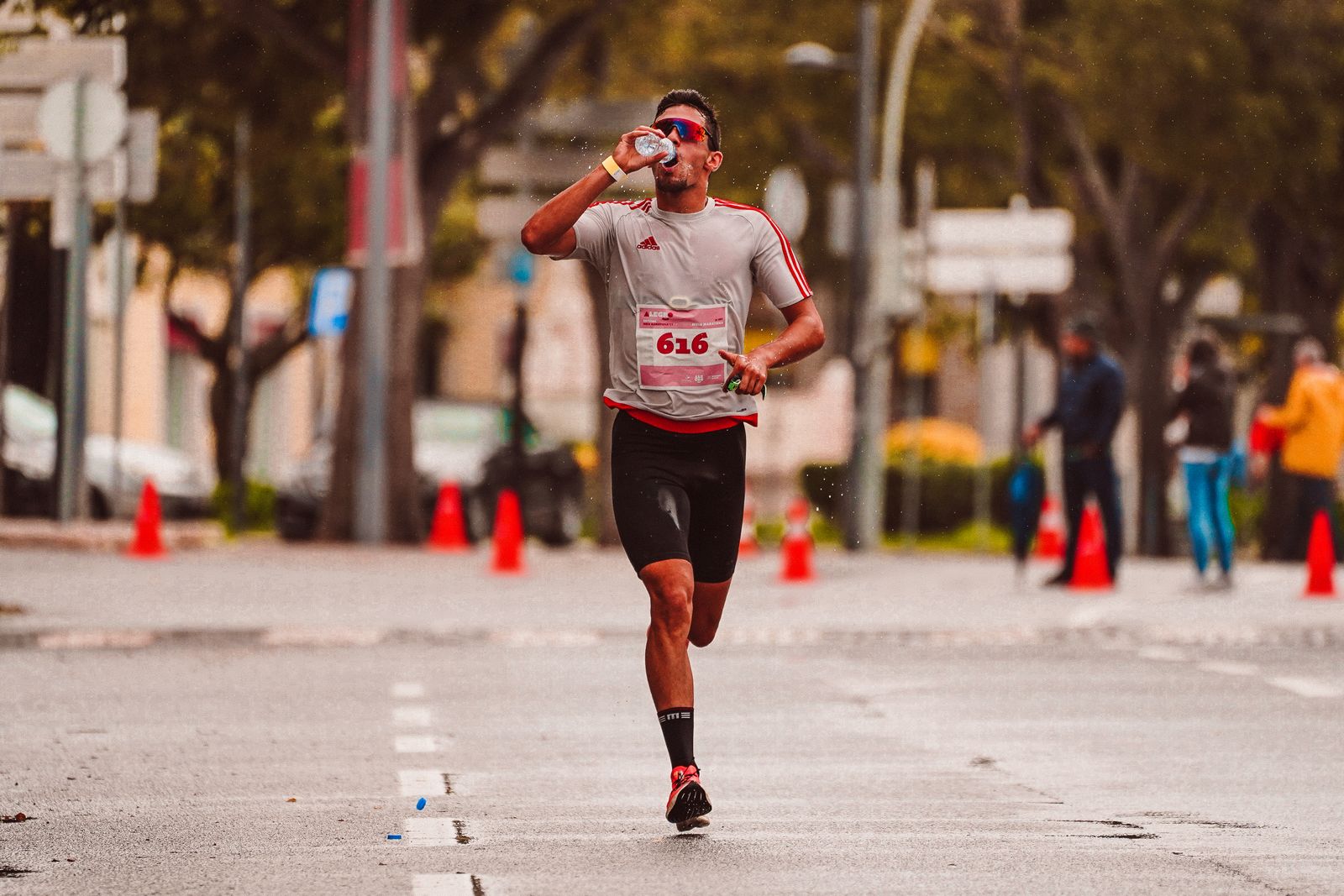 A runner drinking water from a bottle during a run