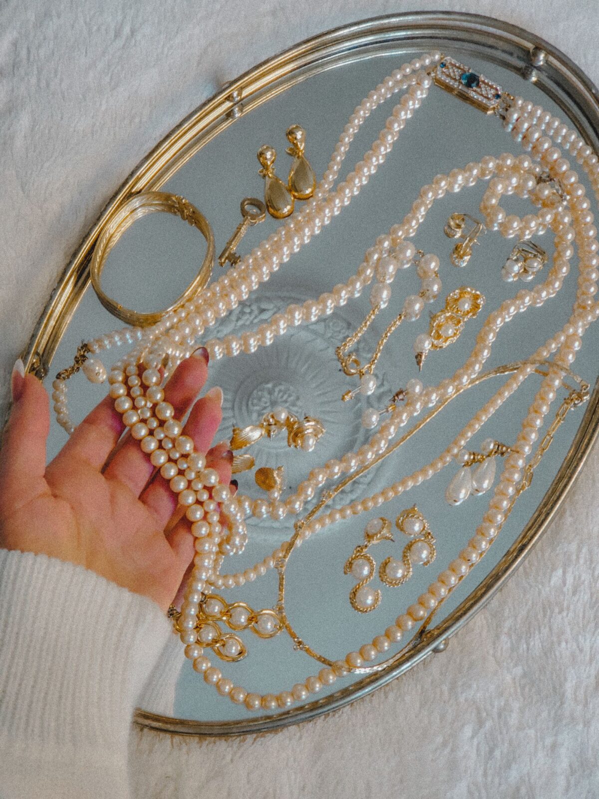 A pearl necklace held on a silver tray