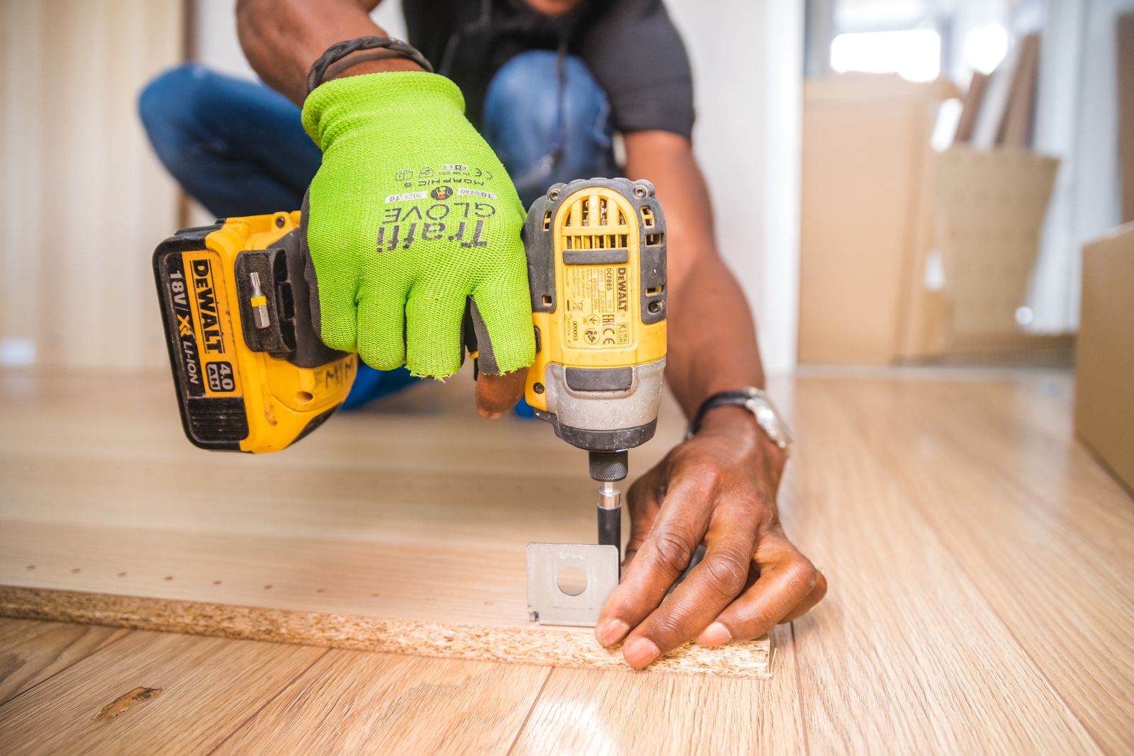 Person using a cordless impact driver to drive a screw into a wood board