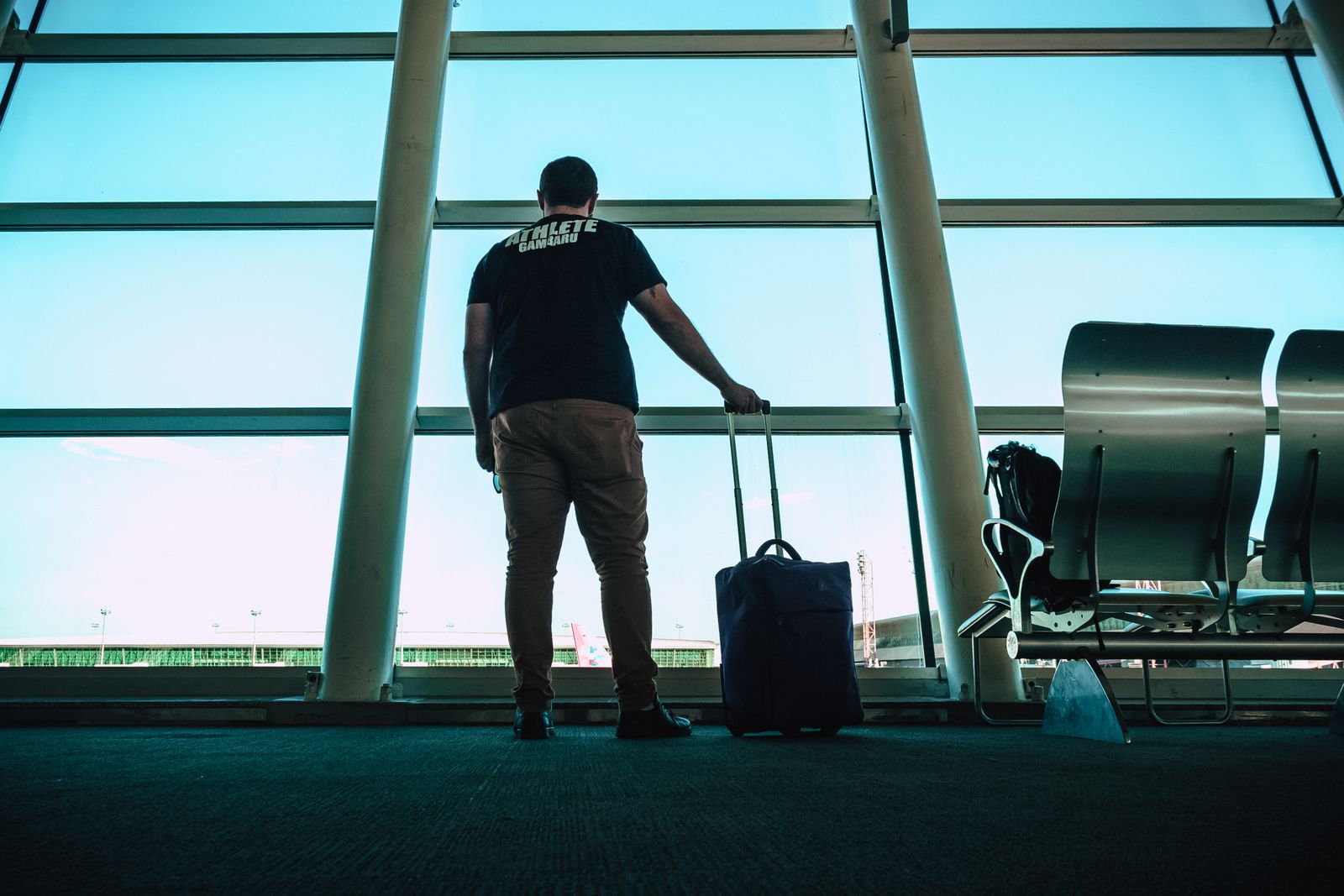 Man holding a piece of luggage while walking through an airport terminal