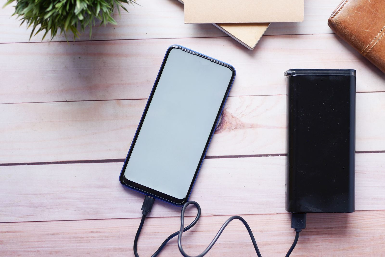 Magnetic wireless power bank with battery display attached to a smartphone on a desk