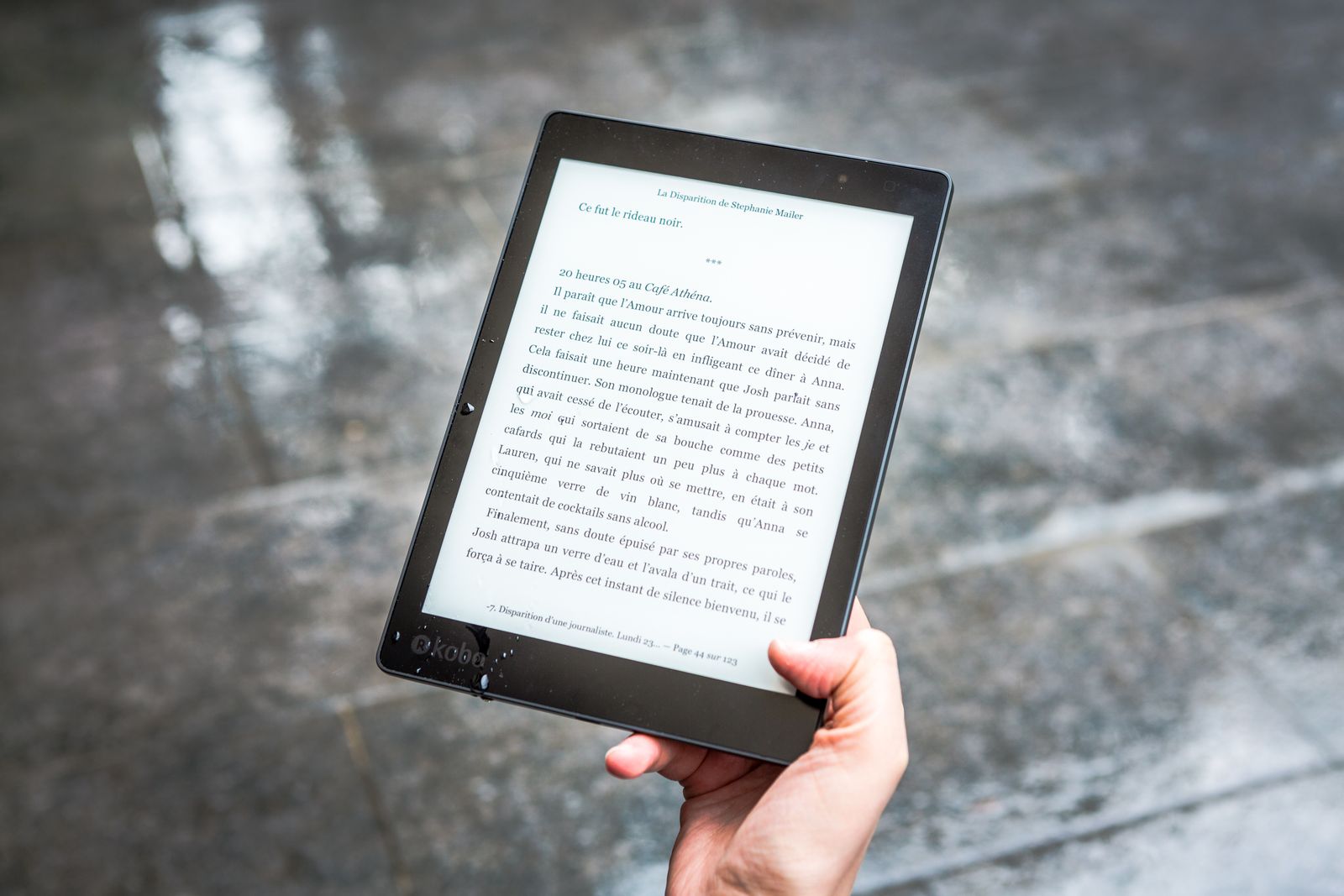 Person holding a black e-ink e-reader device while reading