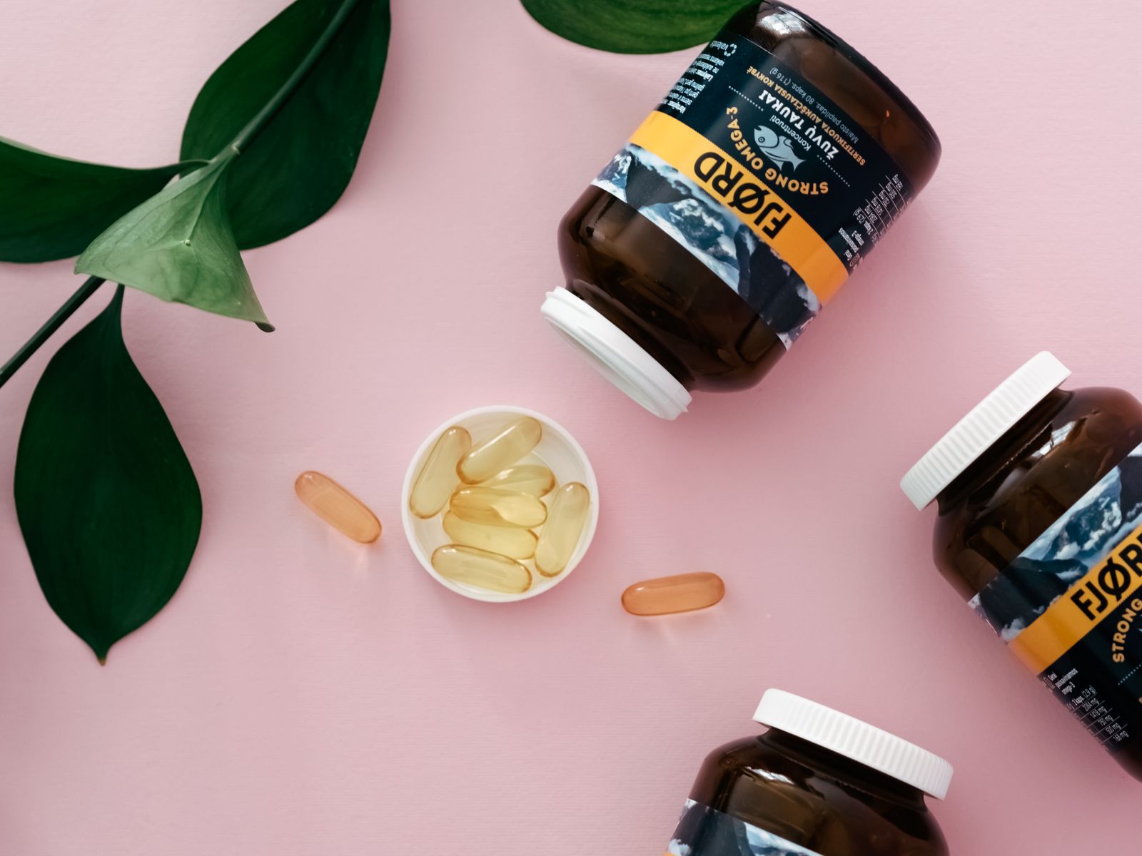 Golden and green omega-3 softgel capsules in an open hand
