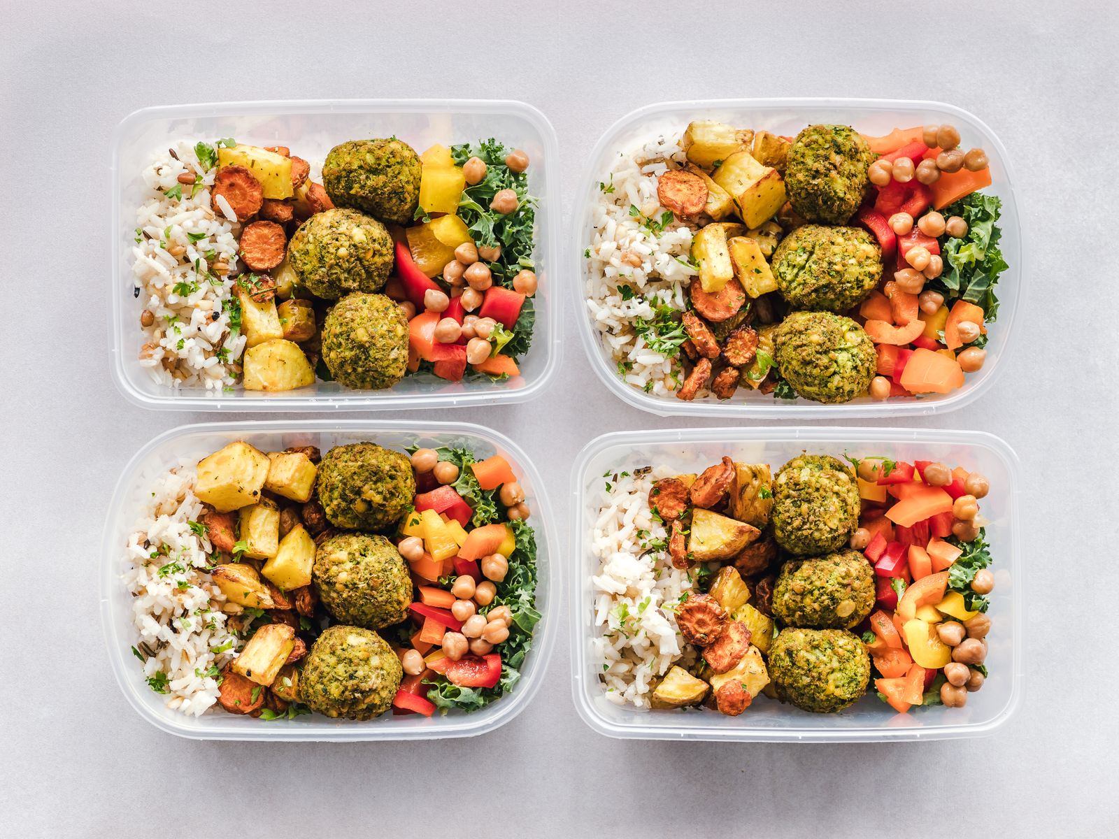Colorful meal-prep containers with vegetables, chickpeas, and rice, representing sustainable healthy-eating habits