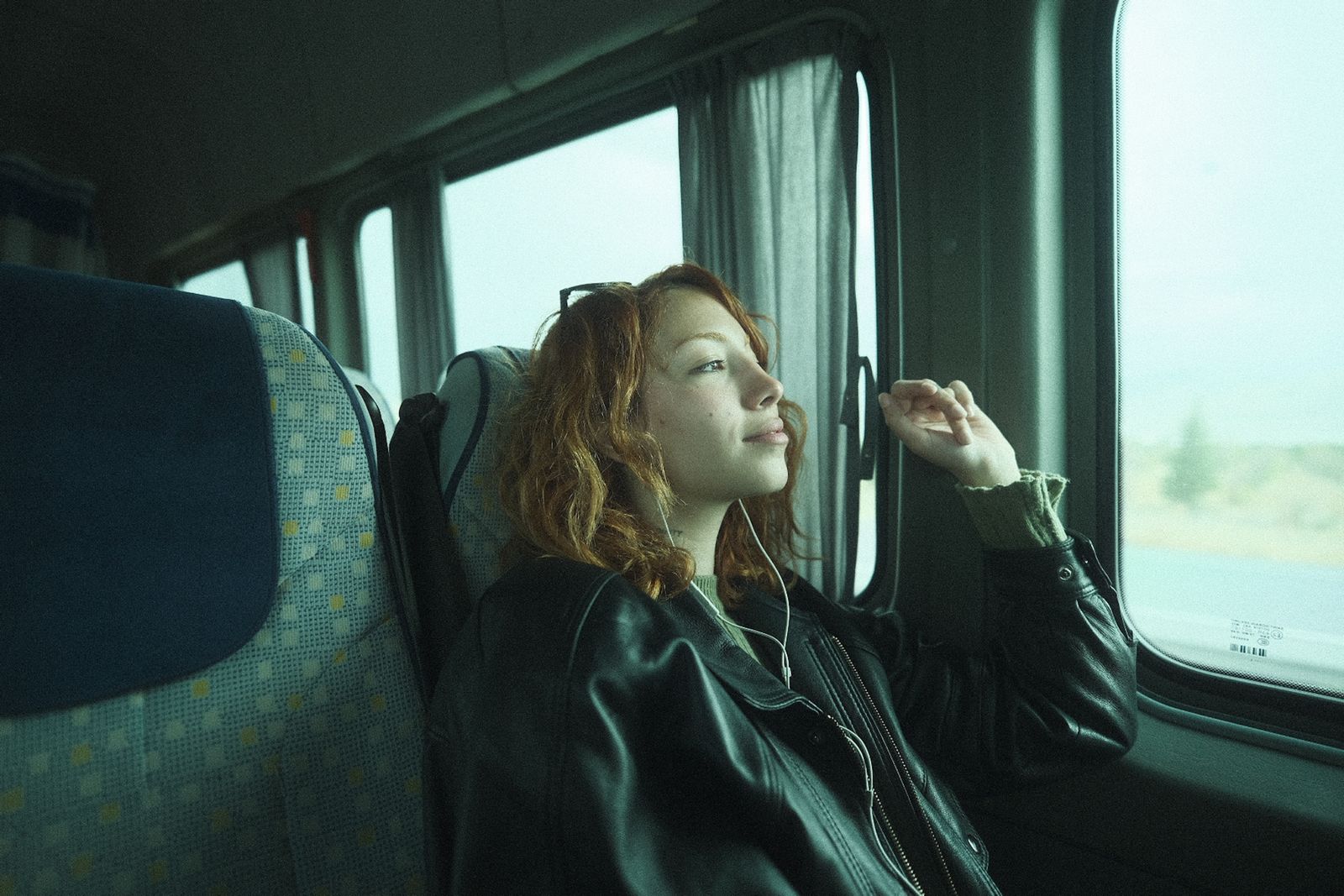 Commuter listening to audio while looking out a train window