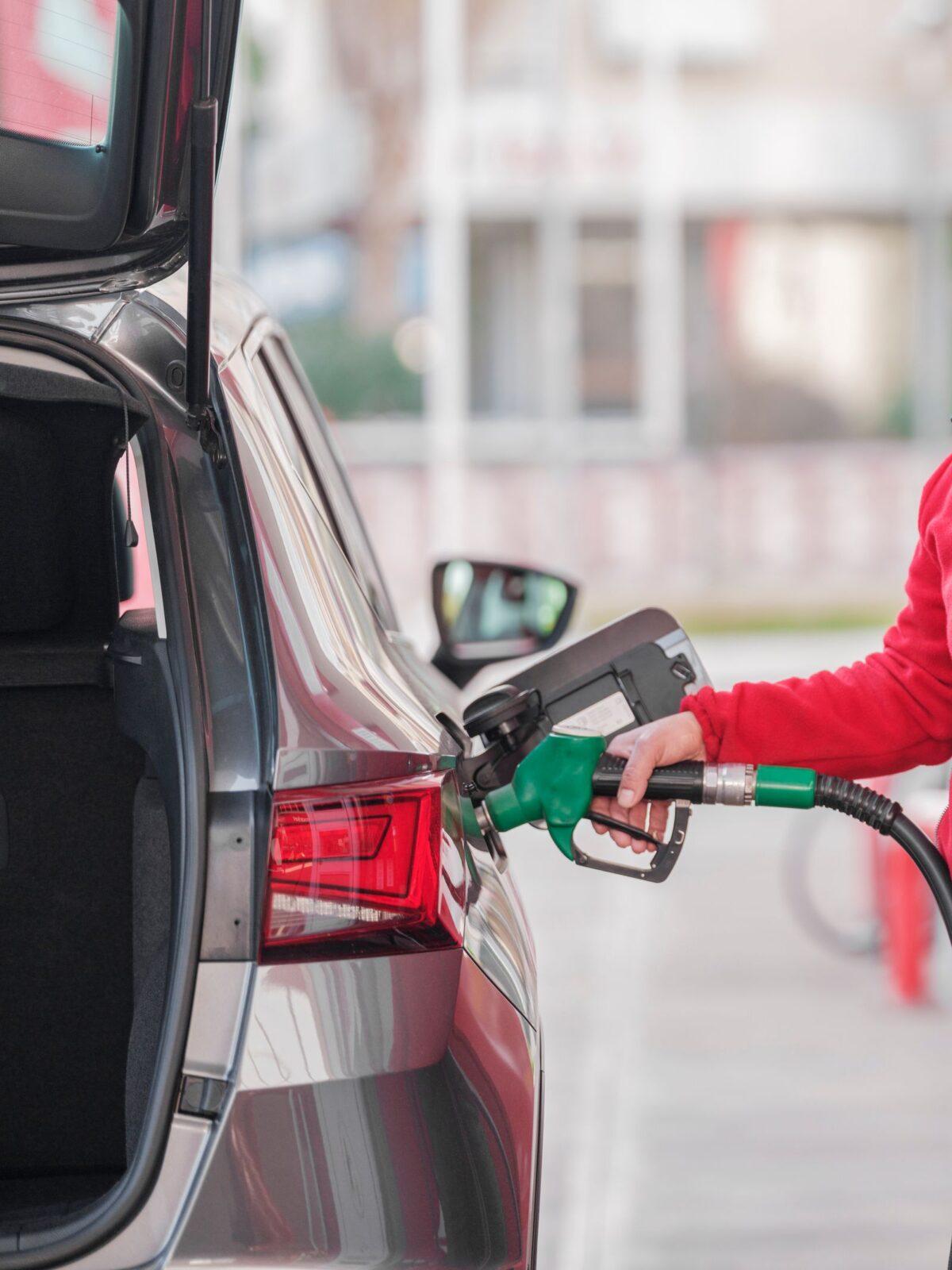 Close-up of a person refueling a car at a gas station pump