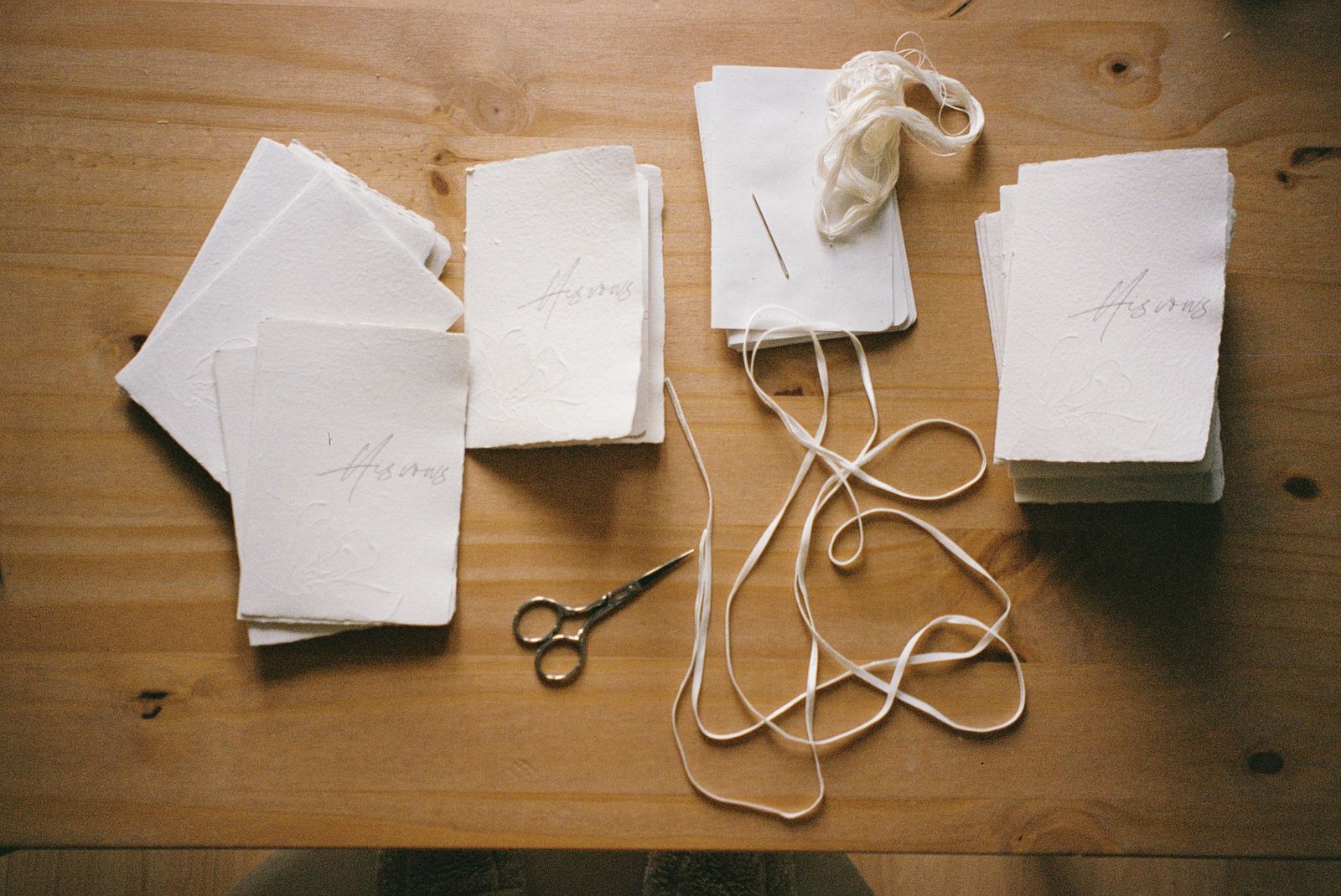 Top view of cut paper, scissors, and ribbon on a wooden table