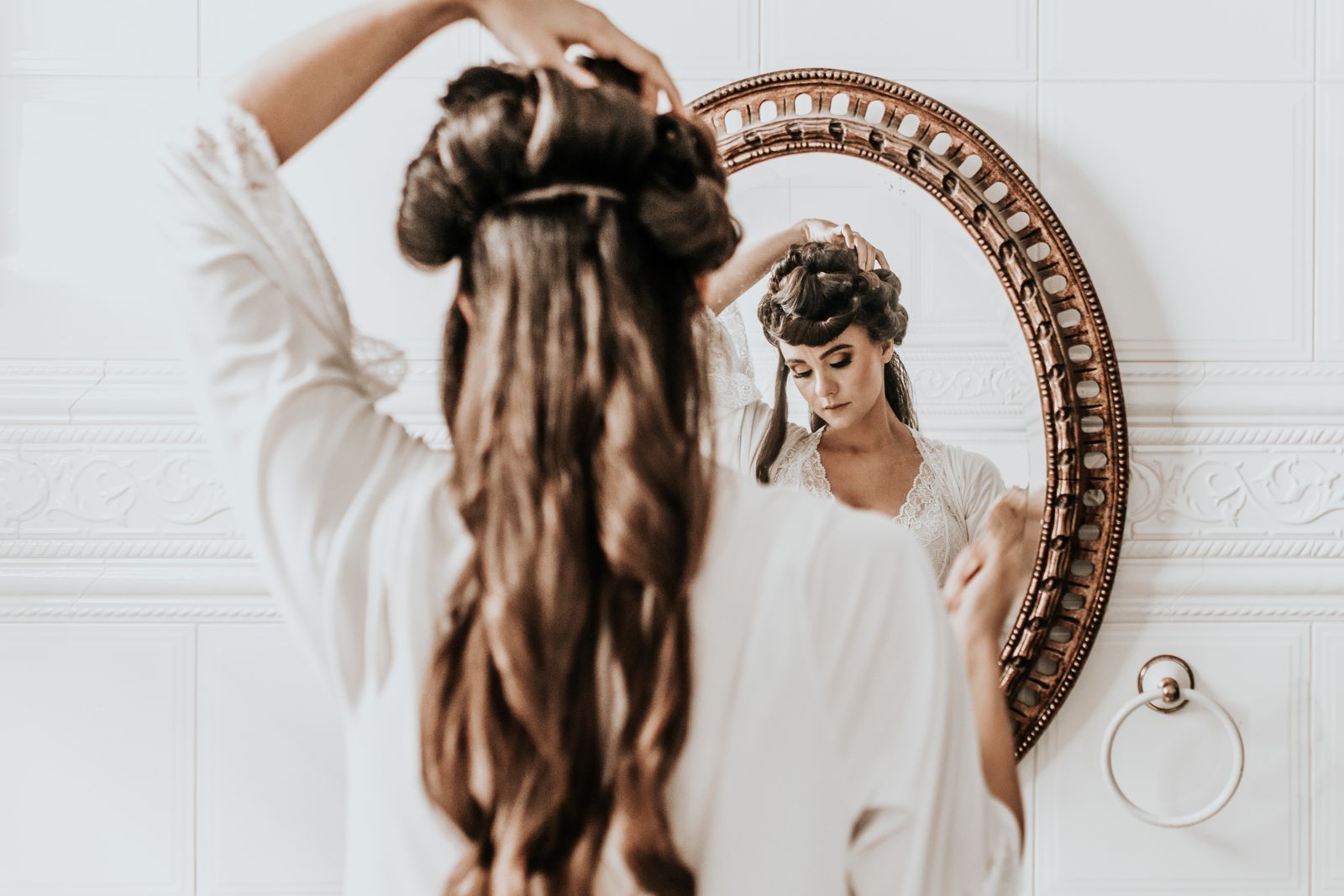 Woman styling soft voluminous waves with an air styler in front of a mirror