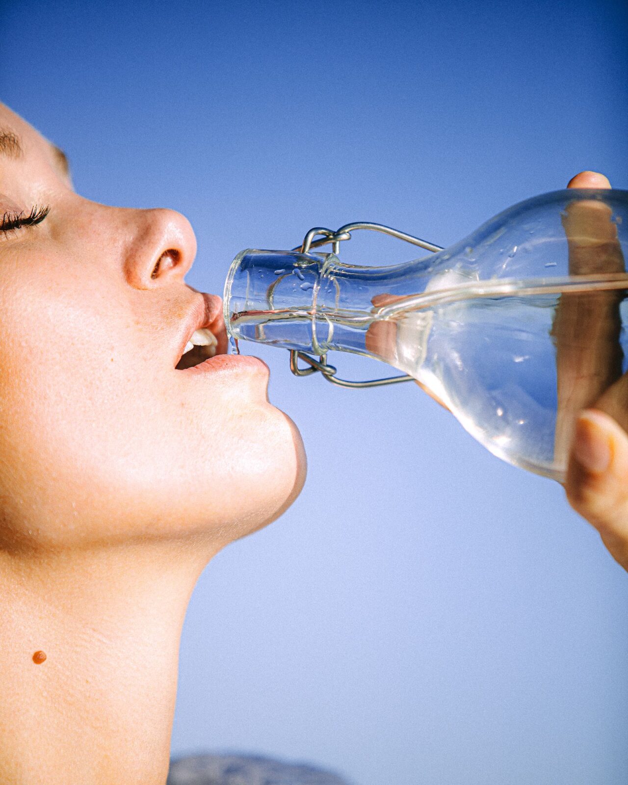 Woman drinking water from a glass bottle to stay hydrated
