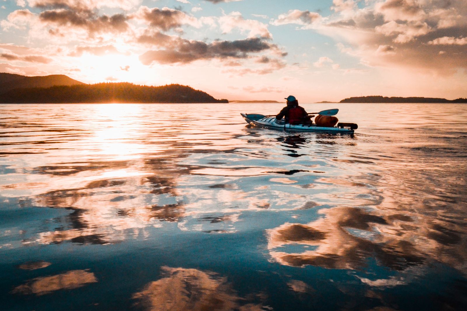 Person sitting on a teal kayak on calm river water