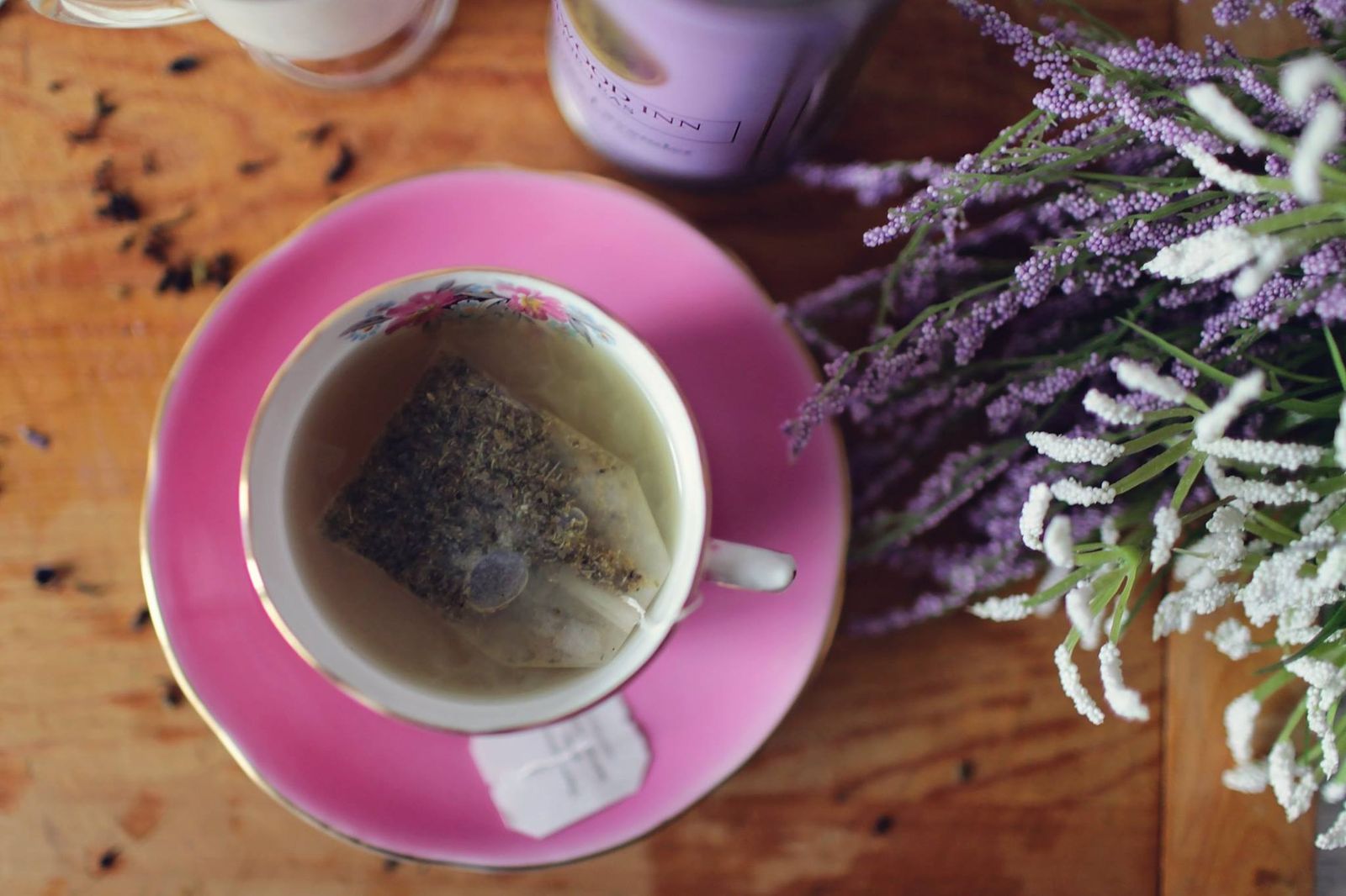 A floral teacup holding herbal tea with visible lavender and botanical ingredients