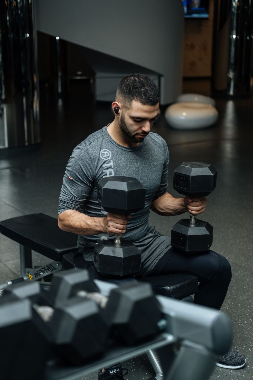 A man sitting on a flat weight bench with a dumbbell
