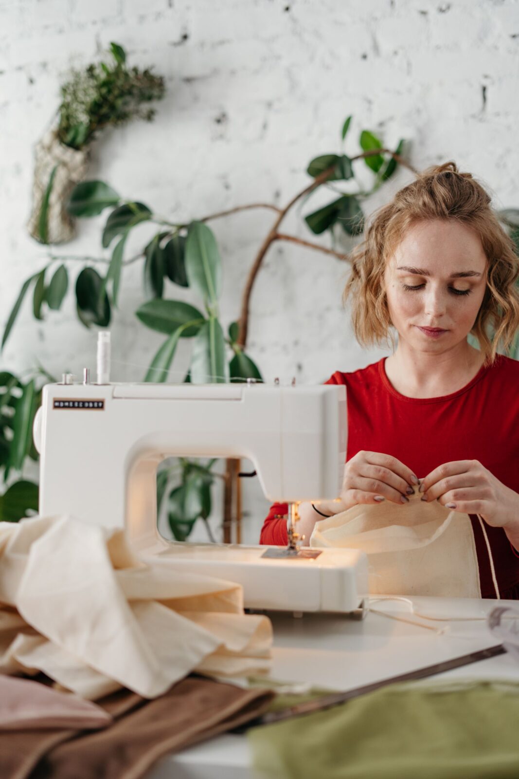 Beginner sewist guiding fabric through a sewing machine