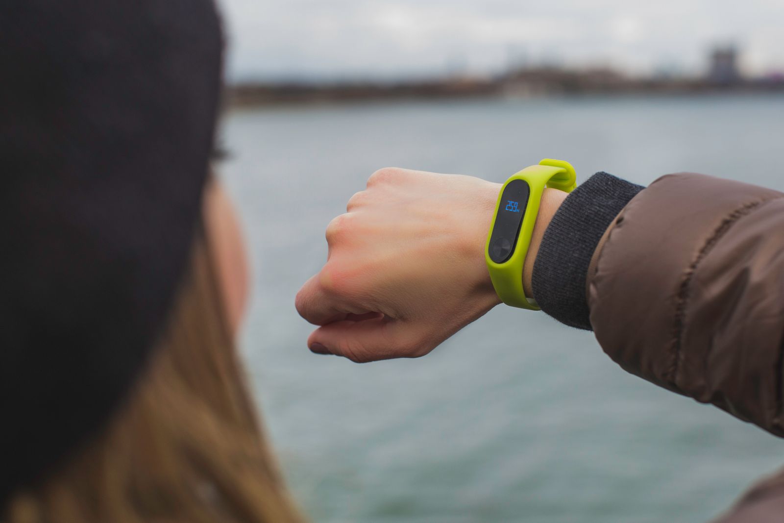 A runner on an outdoor trail checking a GPS fitness watch on their wrist