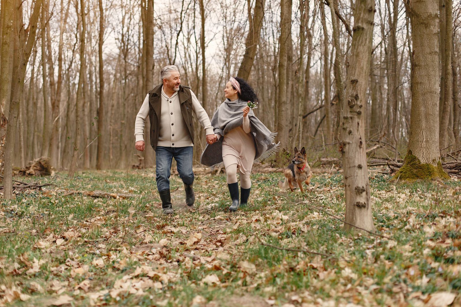 An older couple walking outdoors with their dog