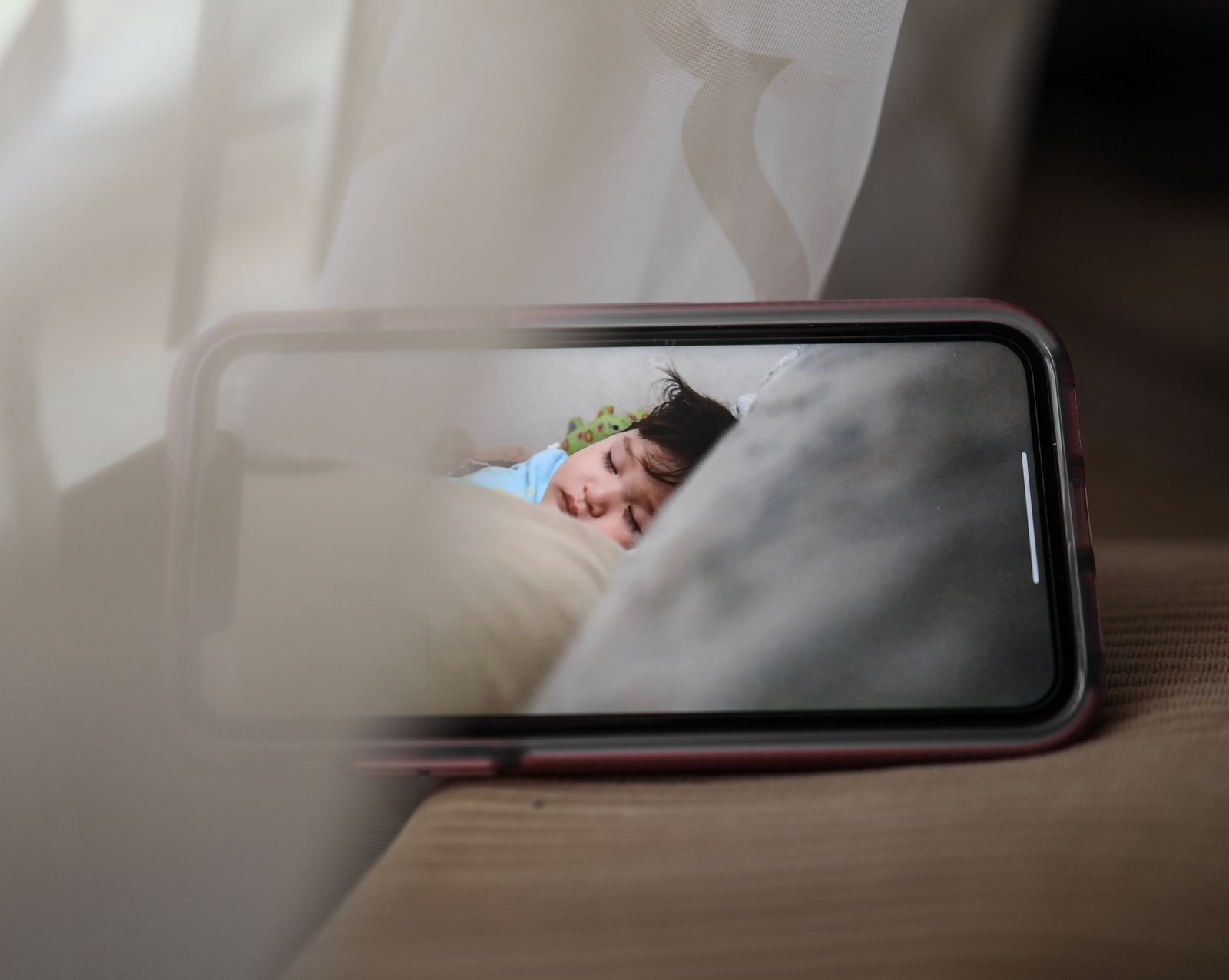 Parent holding a handheld video baby monitor screen at home
