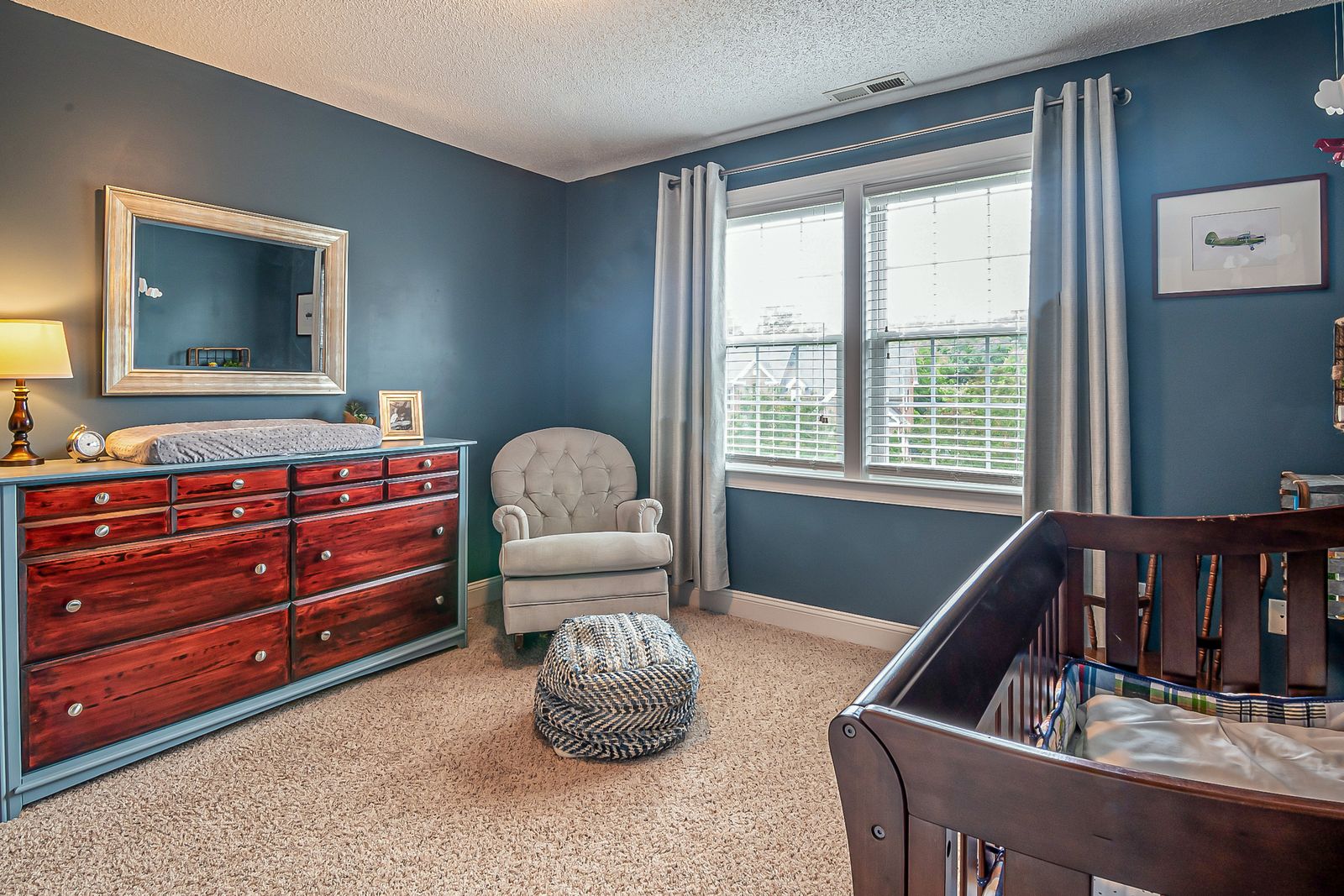 A cozy nursery feeding nook with a comfortable armchair and soft lamp