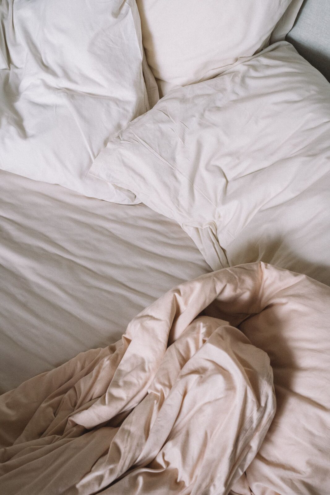 A heavy textured weighted blanket draped over a neatly made bed in soft morning light