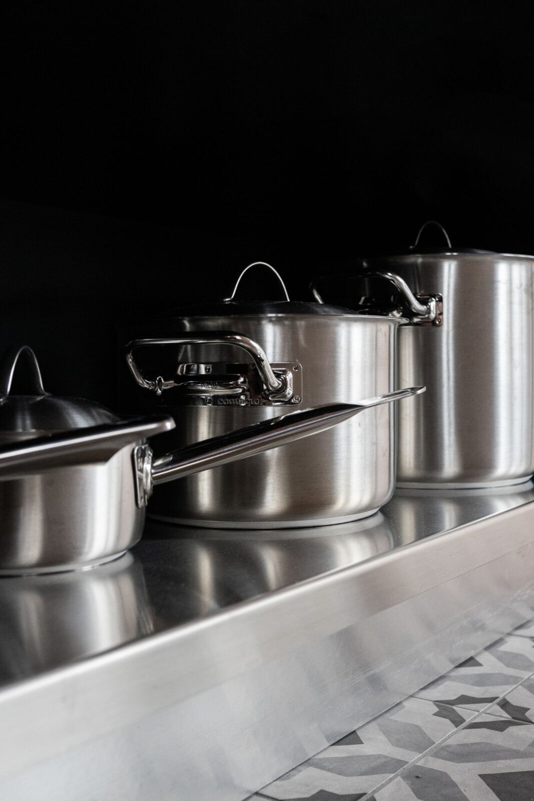 Stainless, cast iron, and nonstick cookware on a wood surface