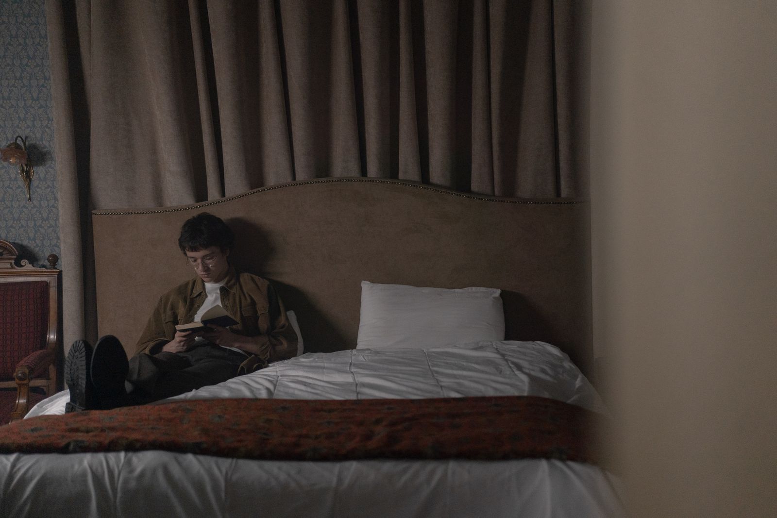 A person sitting up in bed reading a book at night