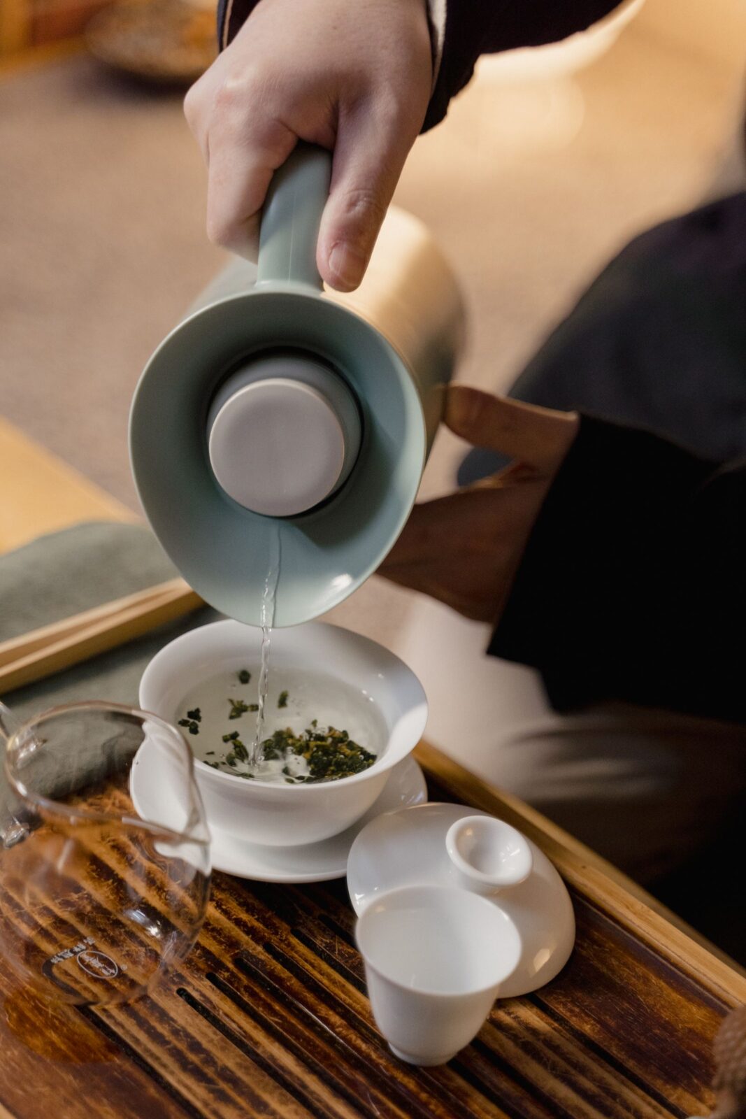 Hot water being poured into a cup over loose herbal tea leaves for a nighttime infusion