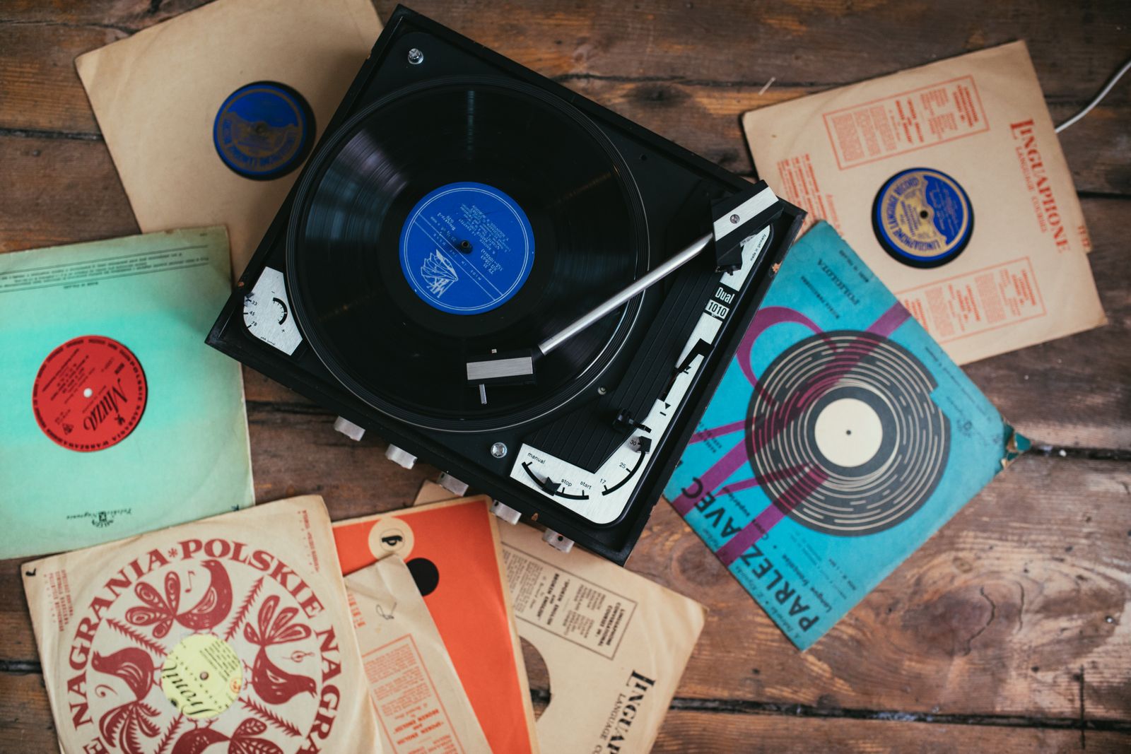 A turntable and a stack of vinyl records on a wooden floor
