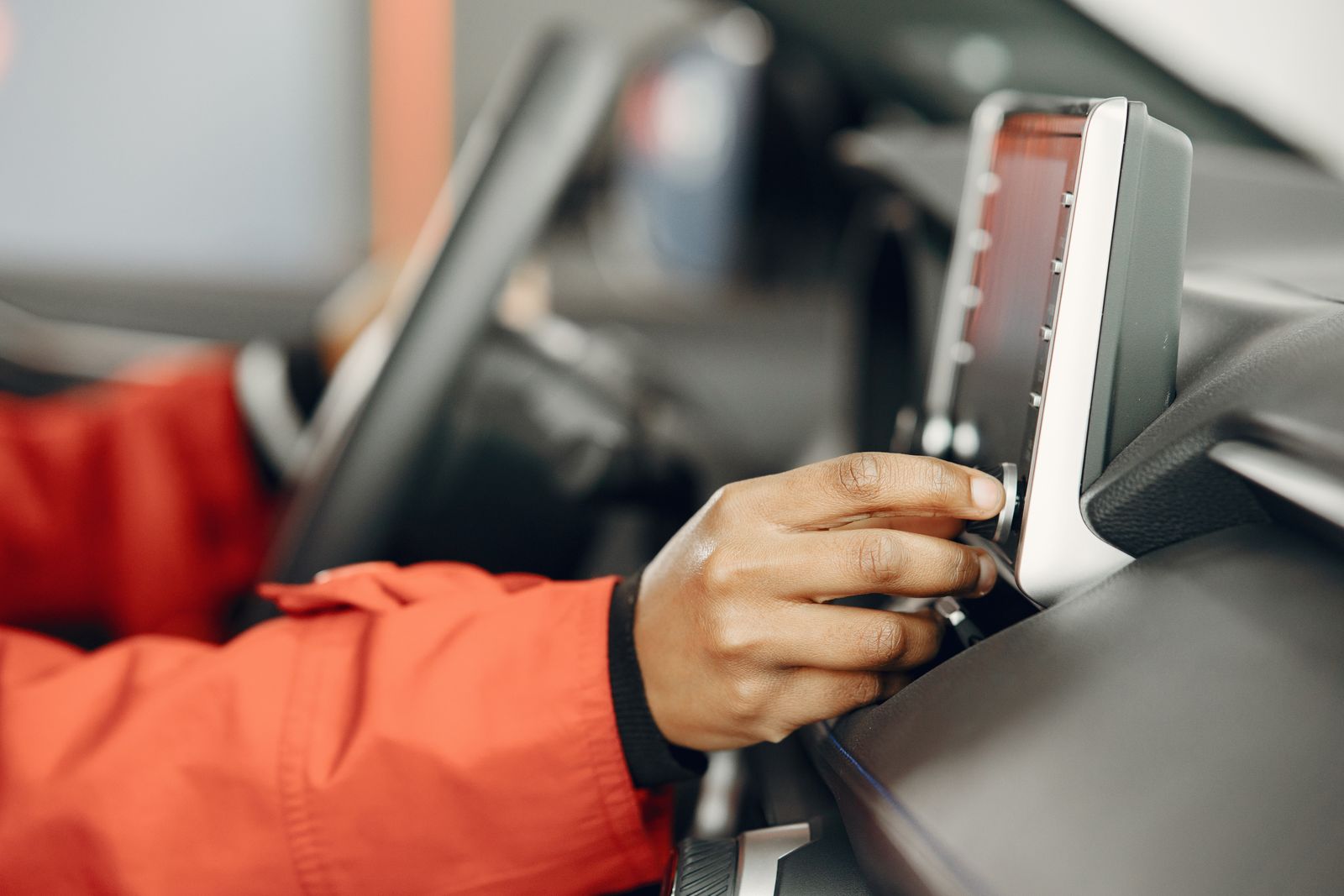 Driver's hand adjusting a car infotainment touchscreen on the dashboard