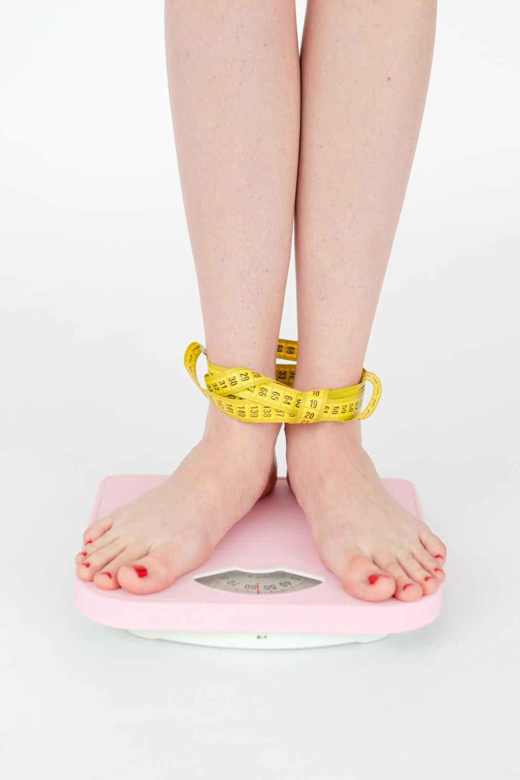 Woman with a measuring tape standing on a bathroom scale