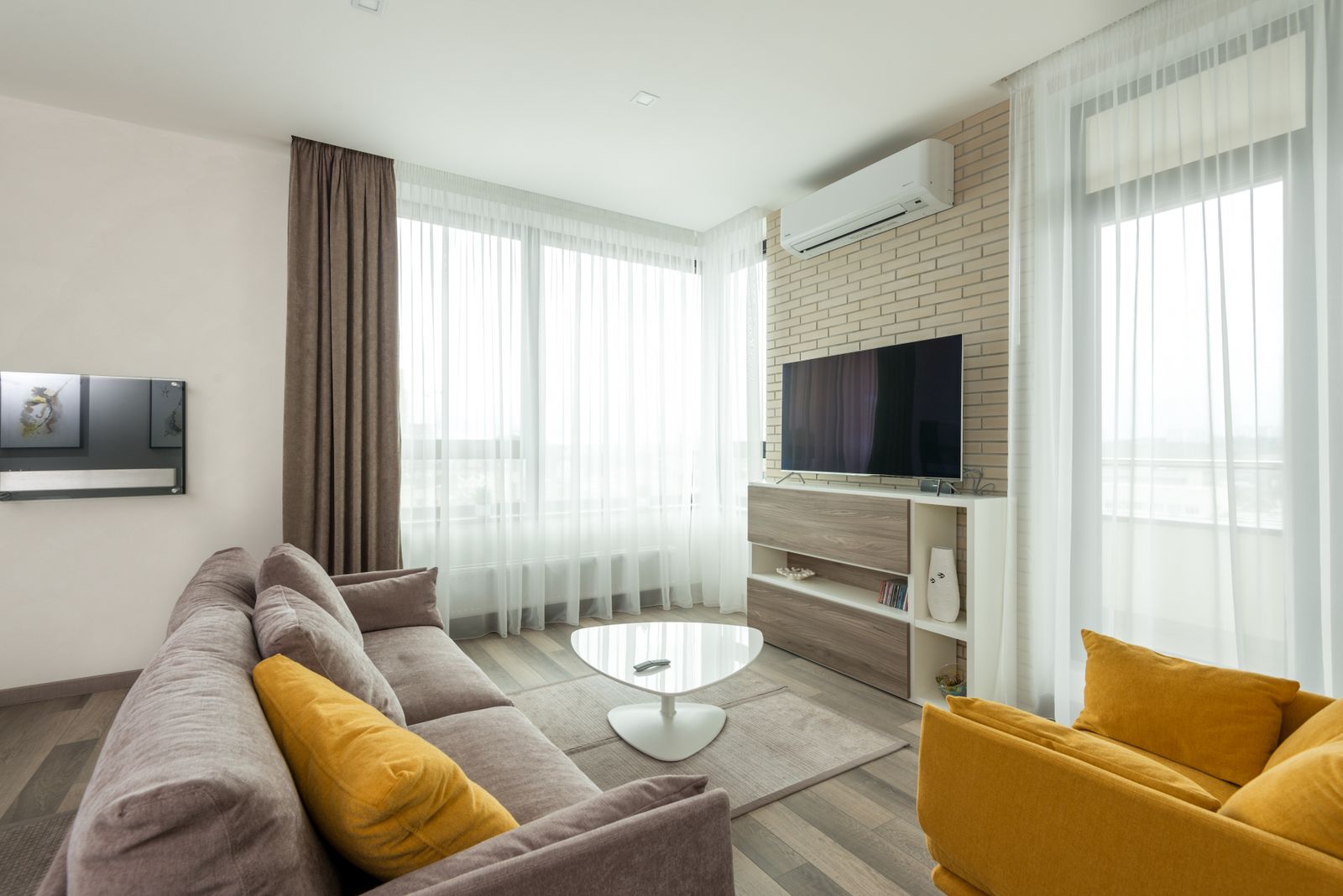 A large flat-screen TV on a living room wall with a sofa at comfortable viewing distance