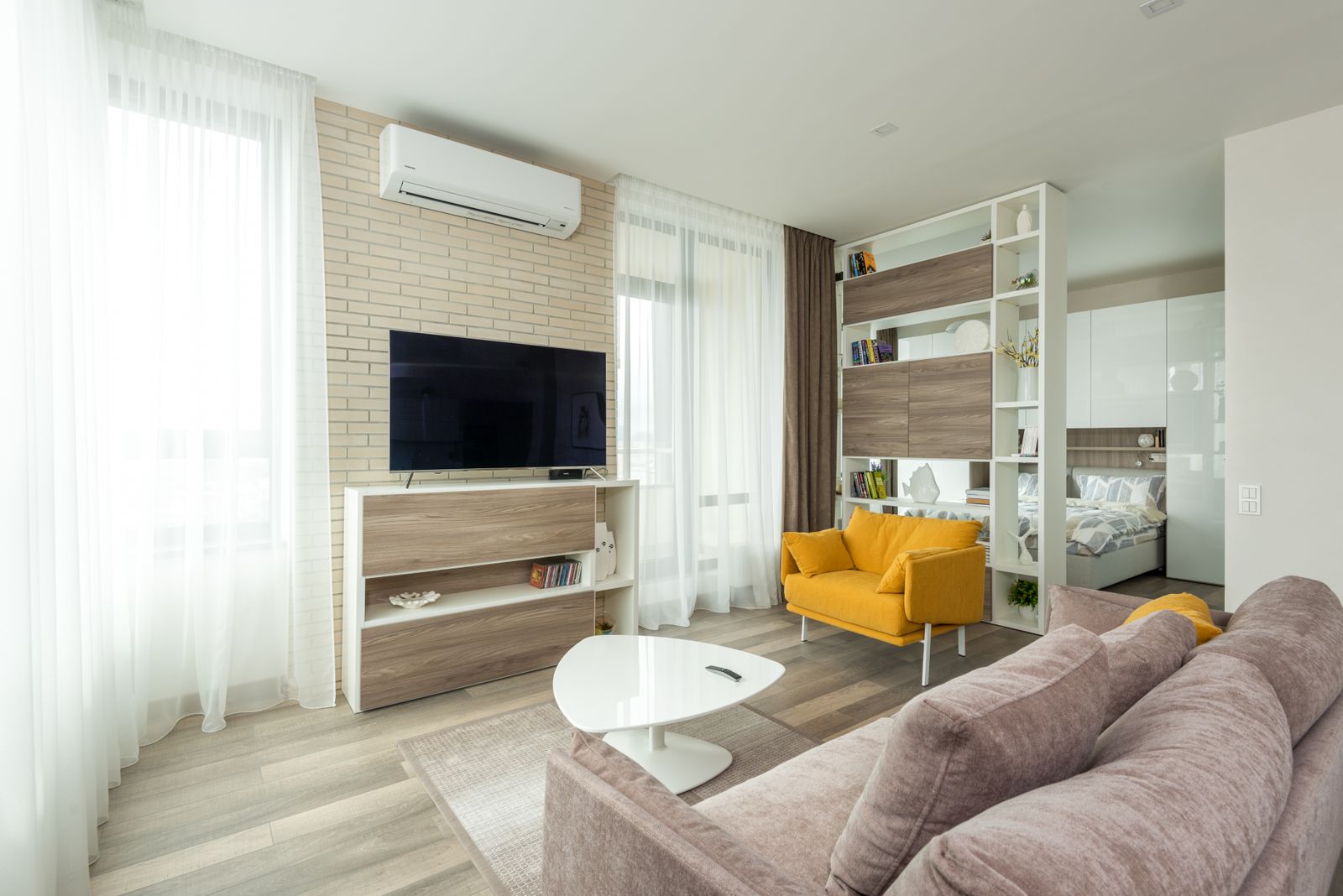 Minimalist studio apartment with open-plan living area and wooden shelving unit