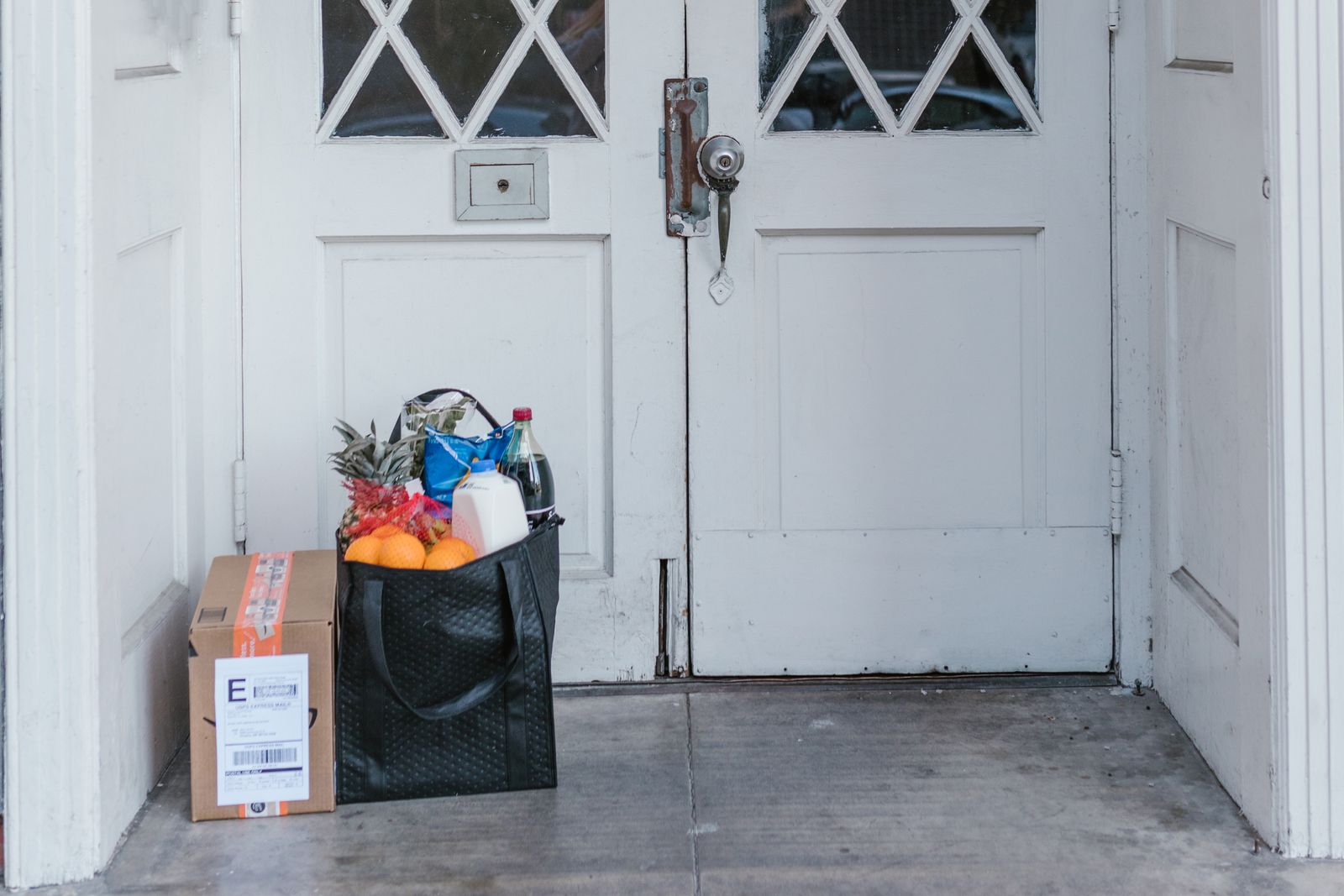 Delivered brown box and groceries beside a front door