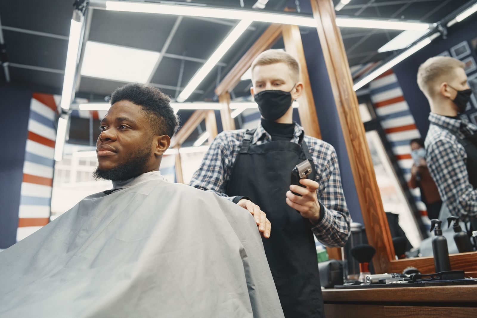 A barber grooming a bearded man's beard in a barbershop