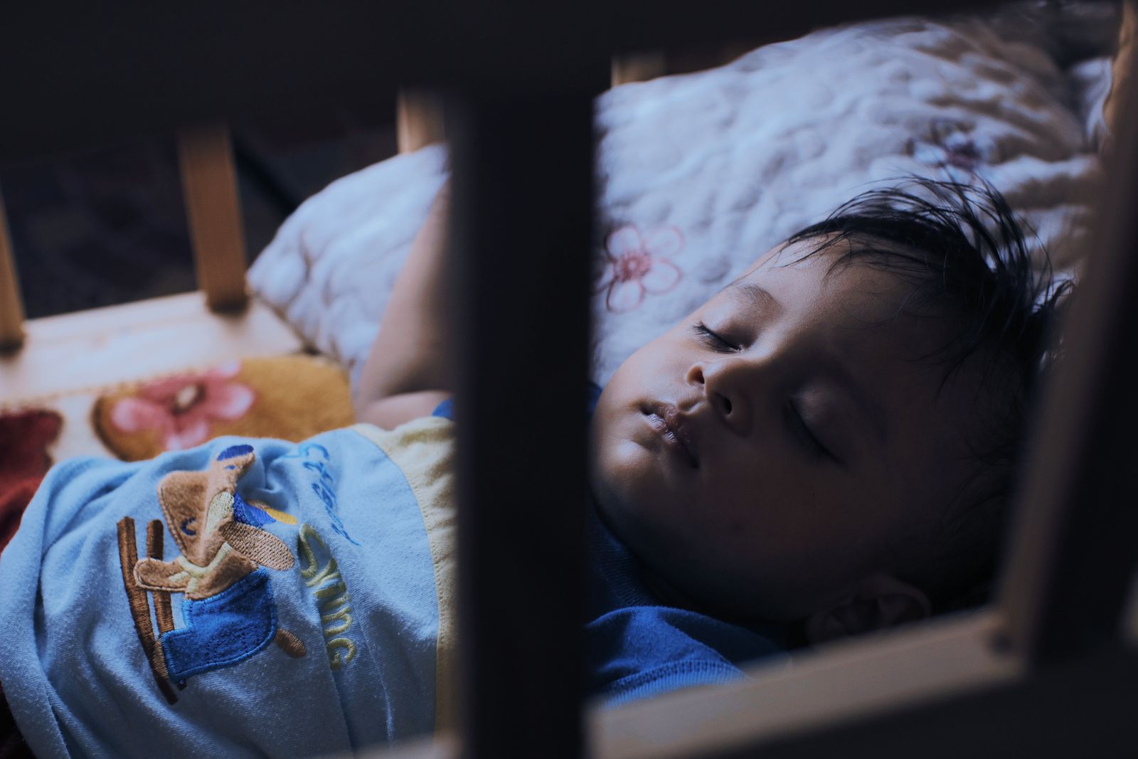 Baby sleeping in a crib with an overhead baby monitor camera above