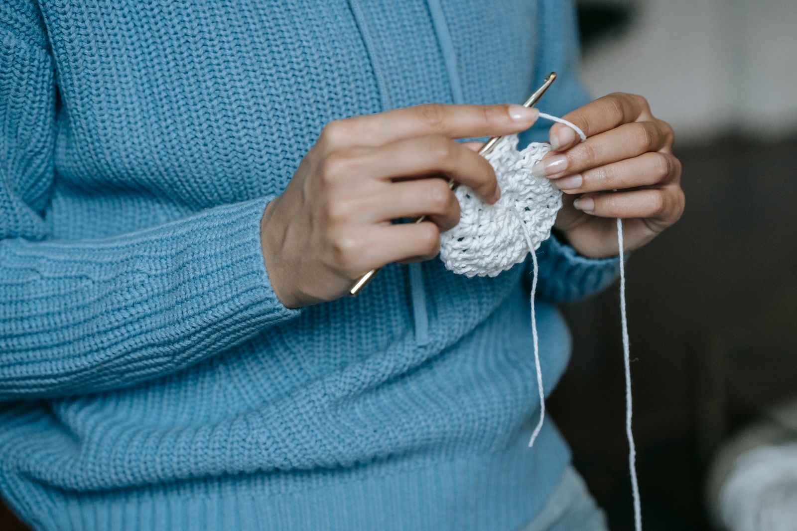 A beginner's hands crocheting a small amigurumi animal with a hook and smooth yarn