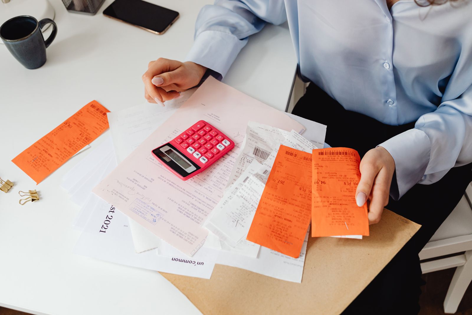 Person holding receipts and using a calculator to track spending