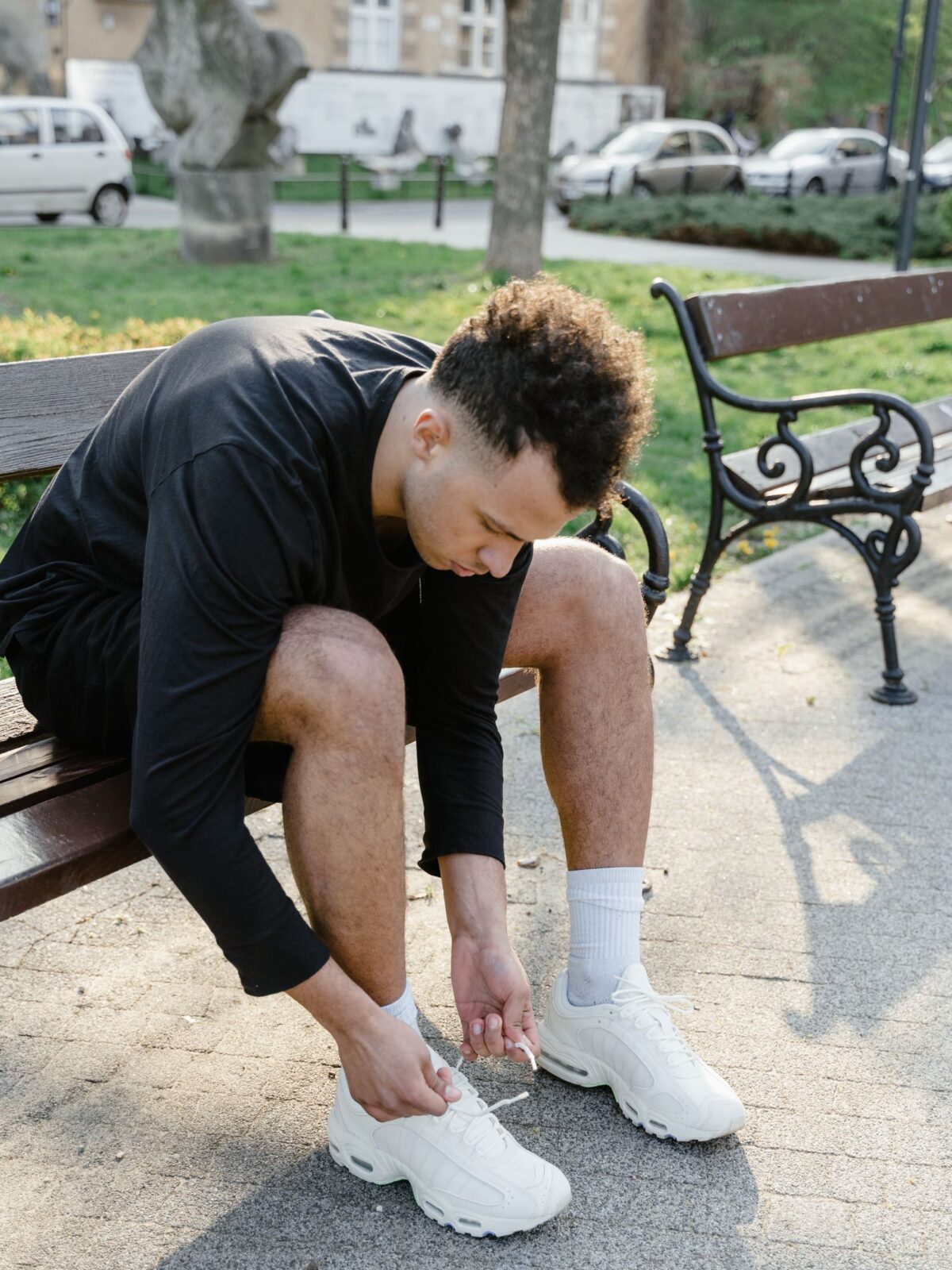 A person sitting on a bench tying a shoe over cushioned socks