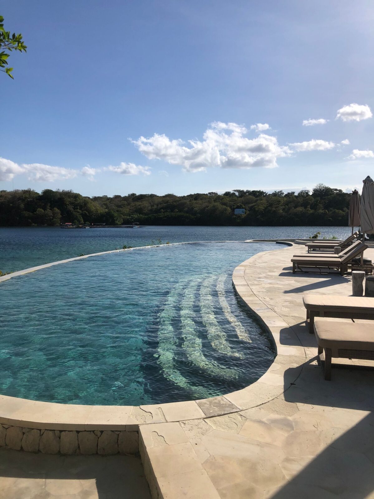 A swimming pool beside the water on a sunny day