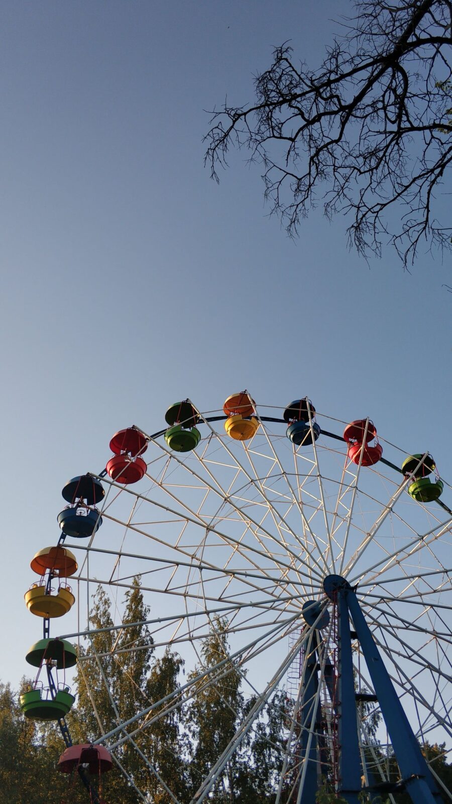 Colorful ferris wheel under a clear blue sky on a hot theme park day