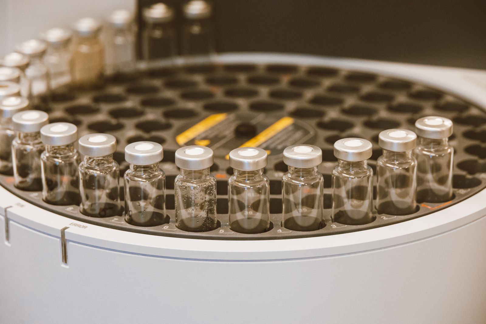 Clear glass medication vials arranged on a tray in a lab setting
