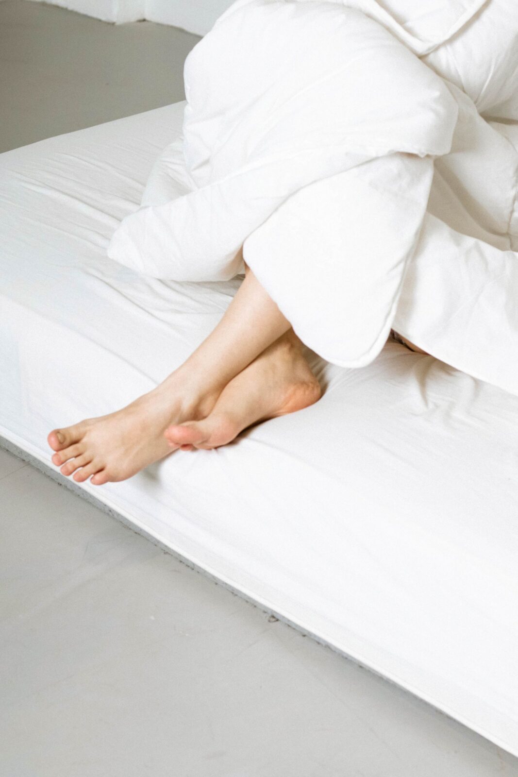 Person wrapped in a warm blanket with feet resting on the bed