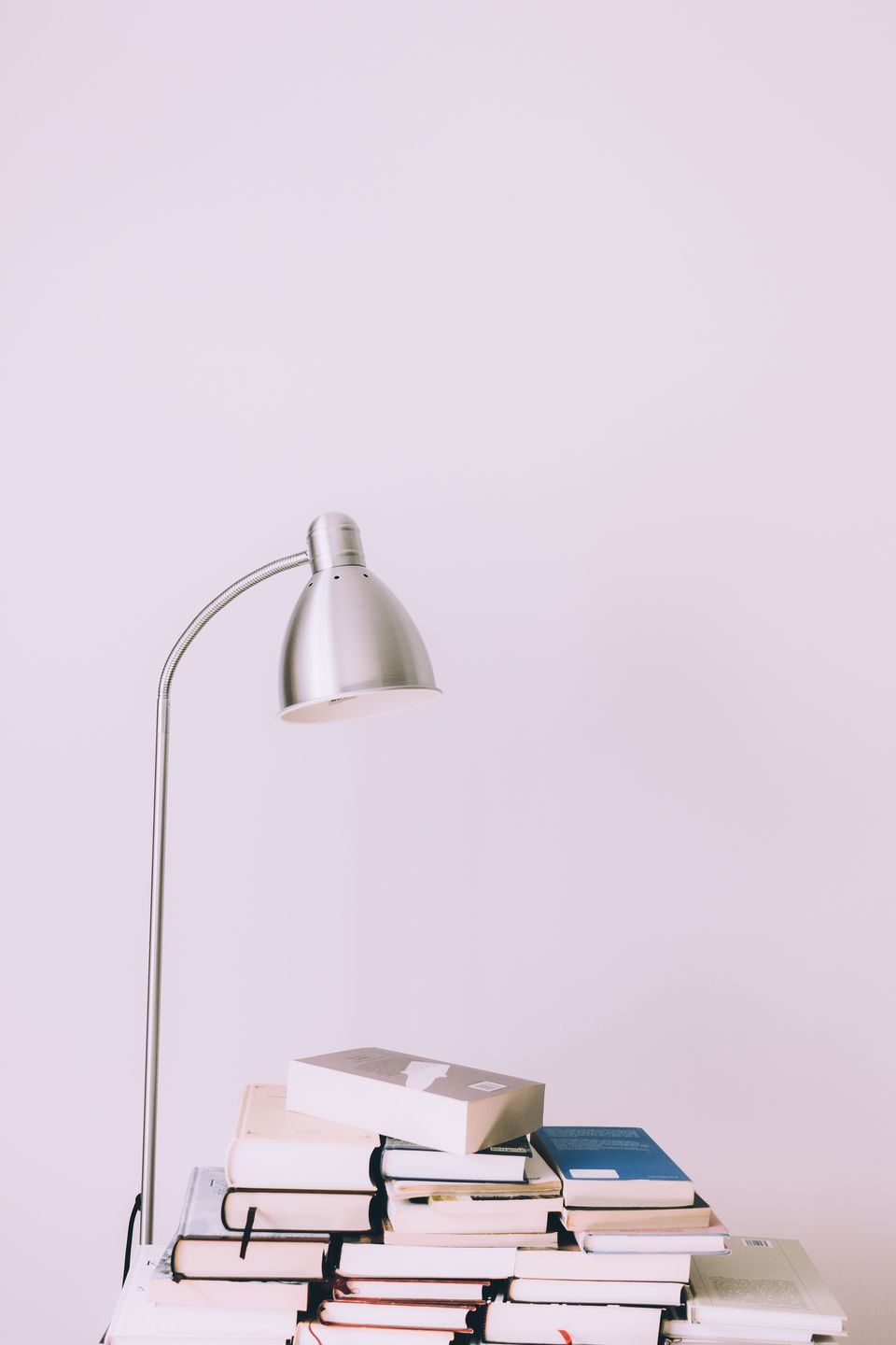Modern silver desk lamp casting bright light over a stack of books