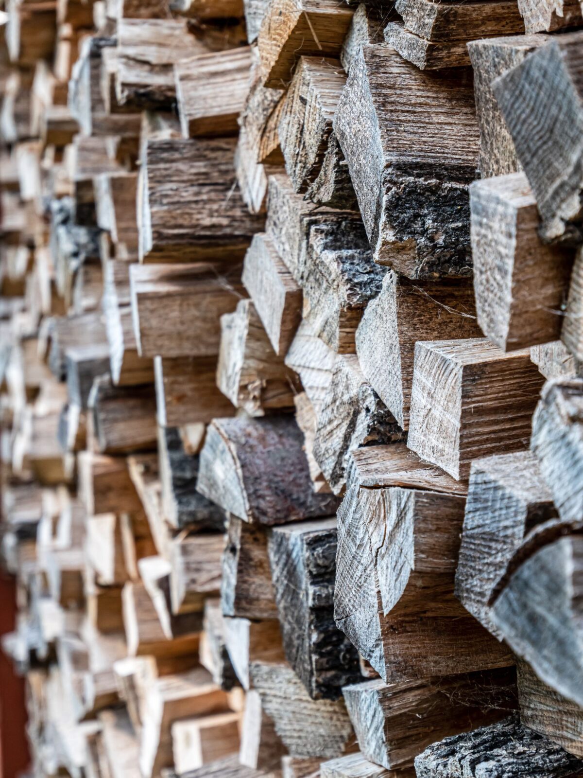 A neat stack of split firewood logs ready to be used in a backyard fire pit