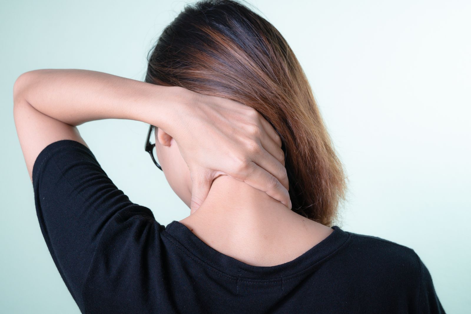 Woman reaching back to massage her own neck