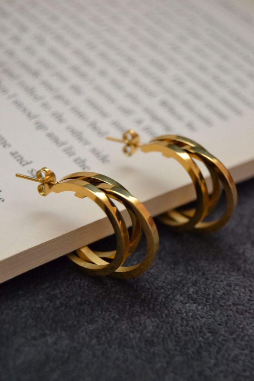 Close-up of gold hoop earrings resting on a neutral textured surface