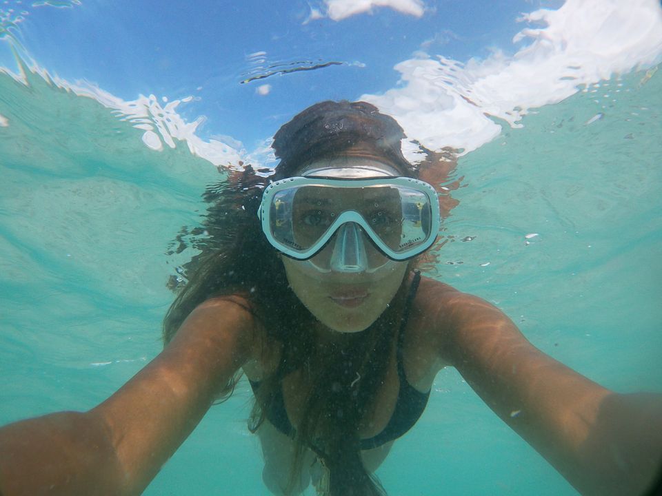 Person snorkeling in clear turquoise ocean water wearing a mask and snorkel