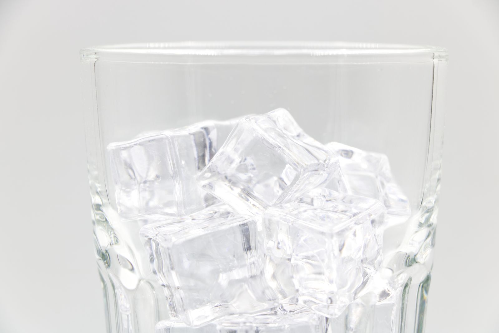 A glass filled with several clear, transparent, square-shaped ice cubes
