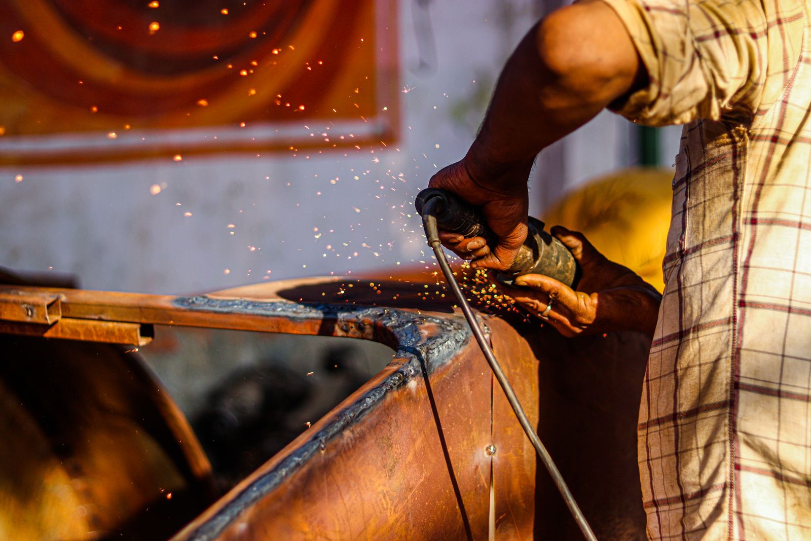 Craftsman using an angle grinder, sparks flying, in a metal fabrication workshop