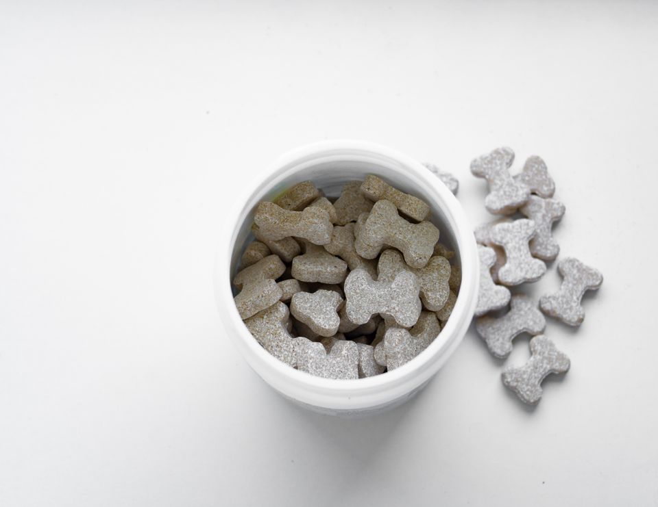 Bone-shaped dog treats arranged in a white container, overhead flat lay