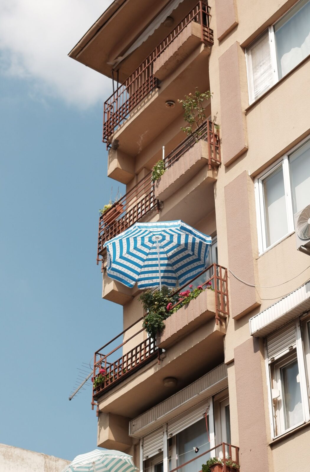 Stacked apartment balconies with an umbrella and potted plants