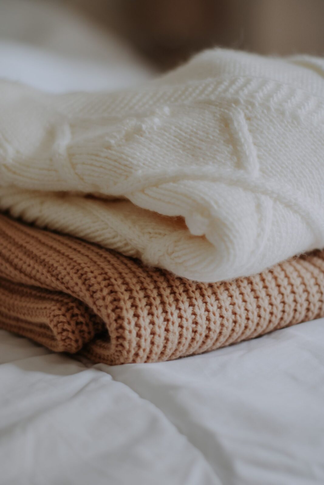 Two folded textured knit sweaters stacked on a white surface